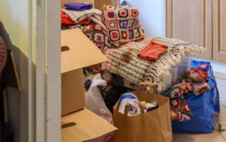 Hoarded room with boxes, bags and blankets piled against a wall before a hoarding and squalor clean up