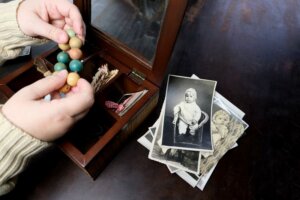 Hands sorting family photos and keepsakes from a wooden box