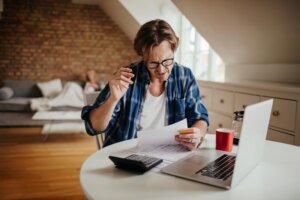 Man reviewing bills at a kitchen table, working out who pays for a hoarding clean up